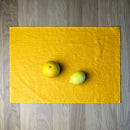 Orange and lemon on Sunny yellow linen placemat on wooden table.